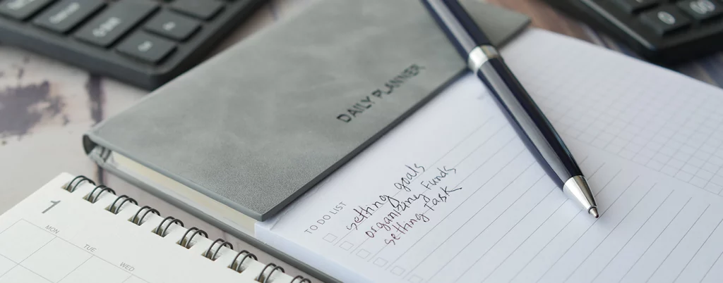 caderno e uma caneta representando a organização/rotina